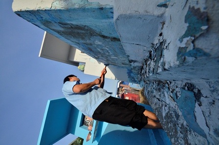 Người dân đang cạo lớp vôi bong tróc để chuẩn bị quét lại lớp vôi mới.