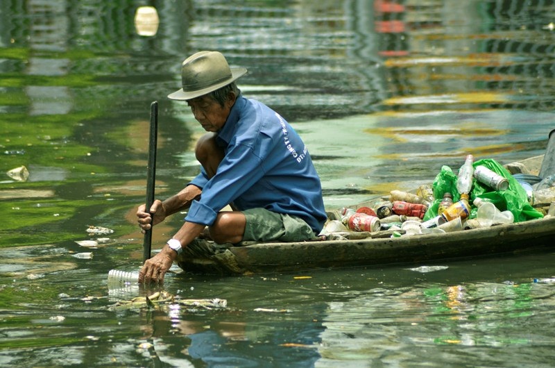 Ông lão nhọc nhằn mưu sinh trên dòng kênh đen - 10 Trên chiếc xuồng cũ kĩ, hàng ngày, ông Bảy ngược dòng kênh đen để mưu sinh và góp ít công sức làm sạch dòng kênh này.