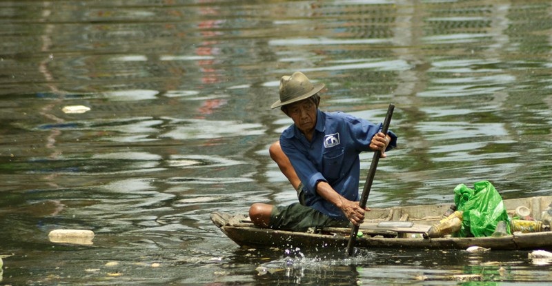 Ông lão nhọc nhằn mưu sinh trên dòng kênh đen - 2 Bơi xuồng trên dòng nước đen ngòm, ông tranh thủ vớt thật nhiều ve chai, phế liệu.