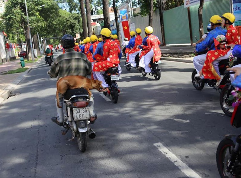Người đi đường tỏ ra ngạc nhiên và thích thú trước cảnh tượng một đám cưới có nhiều cặp đôi.
