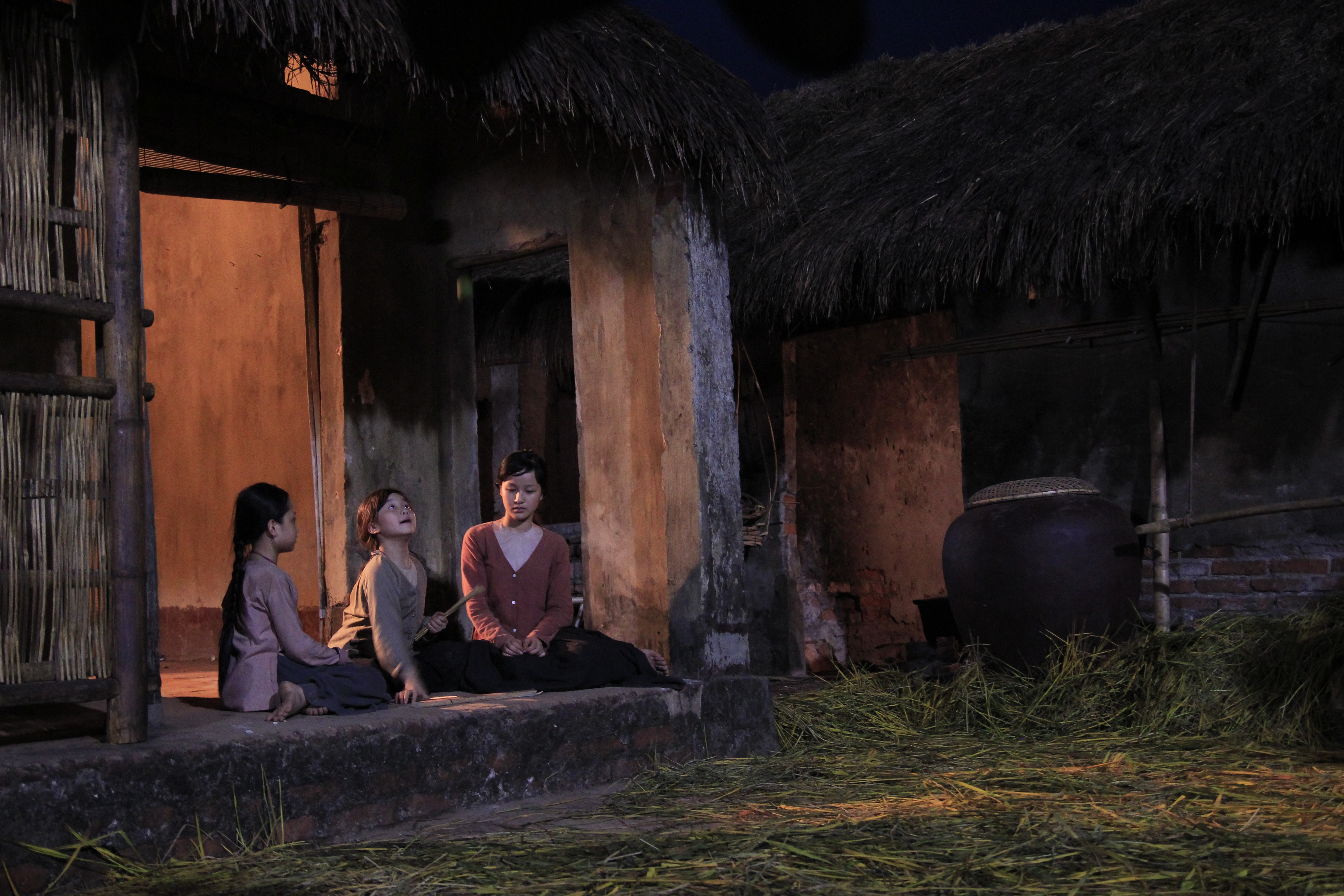 Cảnh ba chị em nhà Yến chơi trò trước hiên nhà.