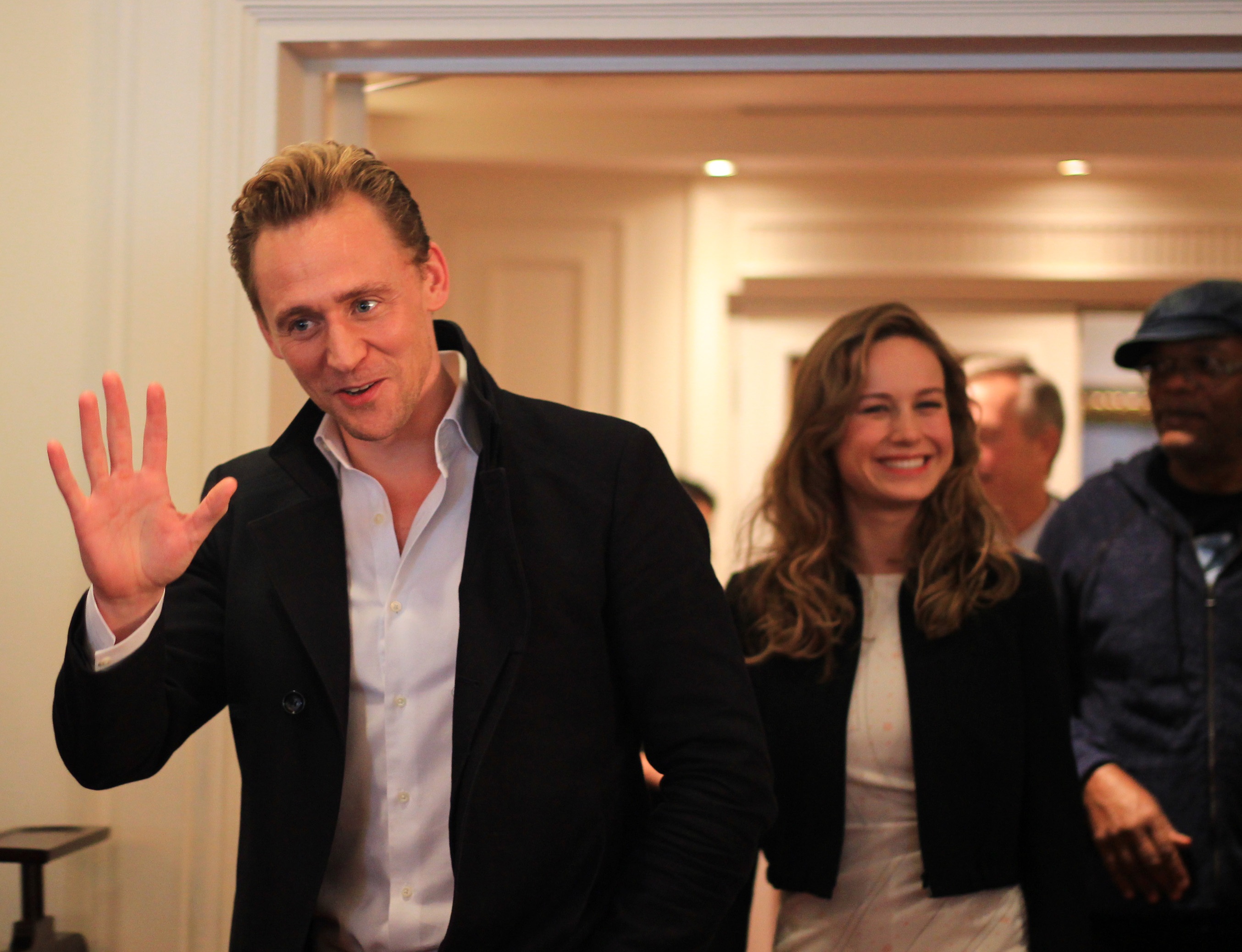 Cận cảnh vẻ điển trai “chết người” của “nam thần” Tom Hiddleston - 1 Tài tử Tom Hiddleston vừa bước vào phòng đã vẫy tay chào và nở nụ cười chết người. Đi sau anh là nữ diễn viên Brie Larson cũng cười rất tươi.
