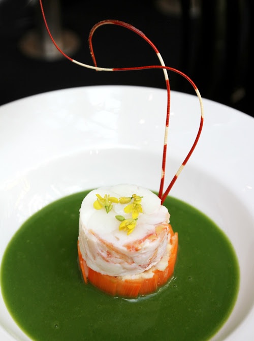 Theo đầu bếp Vũ Văn Thành, các món ăn cũng như ý tưởng trình bày bàn tiệc, lấy cảm hứng từ “cuộc thi ẩm thực” đầu tiên của Việt Nam - sự tích bánh chưng bánh giầy. Trong ảnh: Súp gạo rau bồ ngót với tôm hùm. Màu xanh thể hiện cho trái đất, phần tôm hùm nổi bật như trung tâm của vũ trụ.