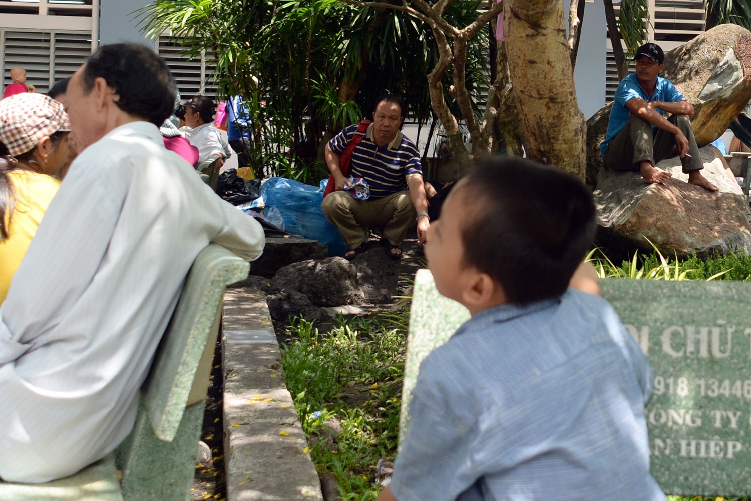 Khói thuốc lá vẫn “hoành hành” trong bệnh viện - 6 Hai người đàn ông hút thuốc trước mặt một em nhỏ đang ngồi chờ khám bệnh