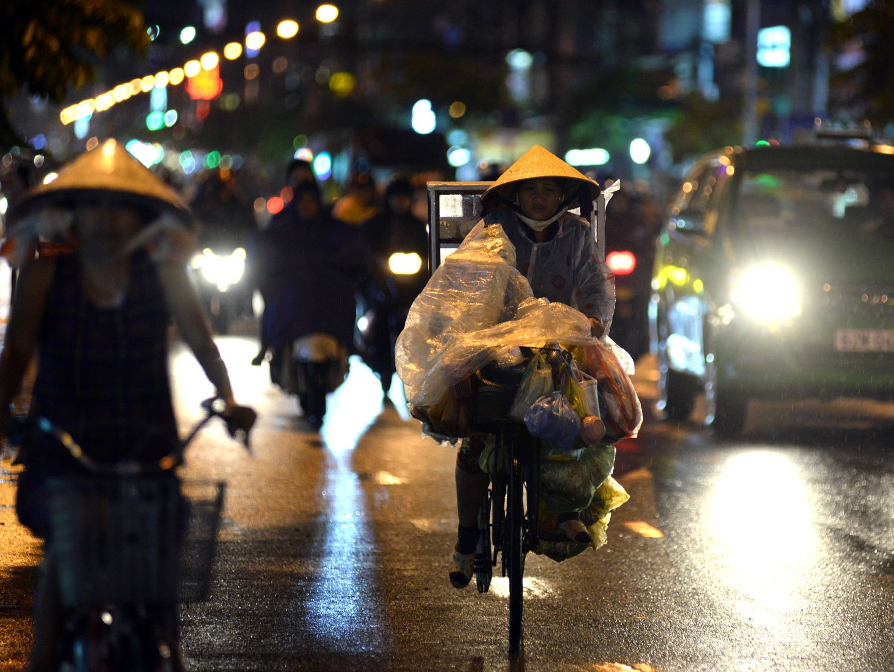 Những phận người nghèo trong đêm mưa Sài Gòn - 11 Người phụ nữ bán bánh tráng trộn che chắn kỹ cho hàng hóa hơn bản thân mình. Chị bảo: “Người ướt thì không sao, chứ hàng hóa mà ướt thì cả nhà chết đói”.