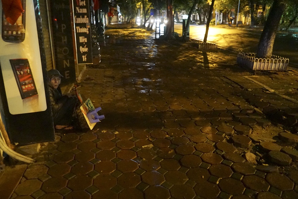 Ông Tống Đức Thành 62 tuổi đang lập cập trong bộ áo mưa để đón khách vá xe trên phố Bà Triệu.