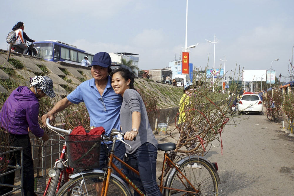 Khách mua đào chụp ảnh lưu niệm vui vẻ tại chợ.