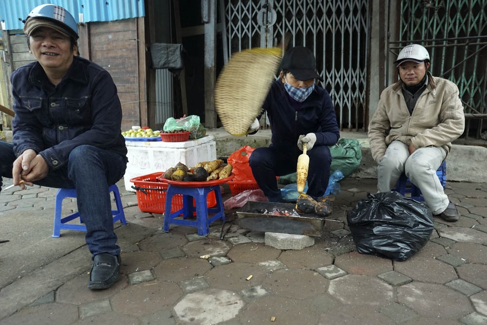 Người Hà Nội co ro trong đợt rét mạnh nhất kể từ đầu mùa - 8 Nhiều người ở ngoài đường co ro bên bếp than nướng ngô.
