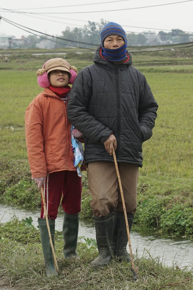 Nông dân Hà Nội lội ruộng trong cái rét cắt da cắt thịt - 8 Em Hường và người hàng xóm là anh Nguyễn Văn Thận trong bộ quần áo chống rét khi đi chăn bò.