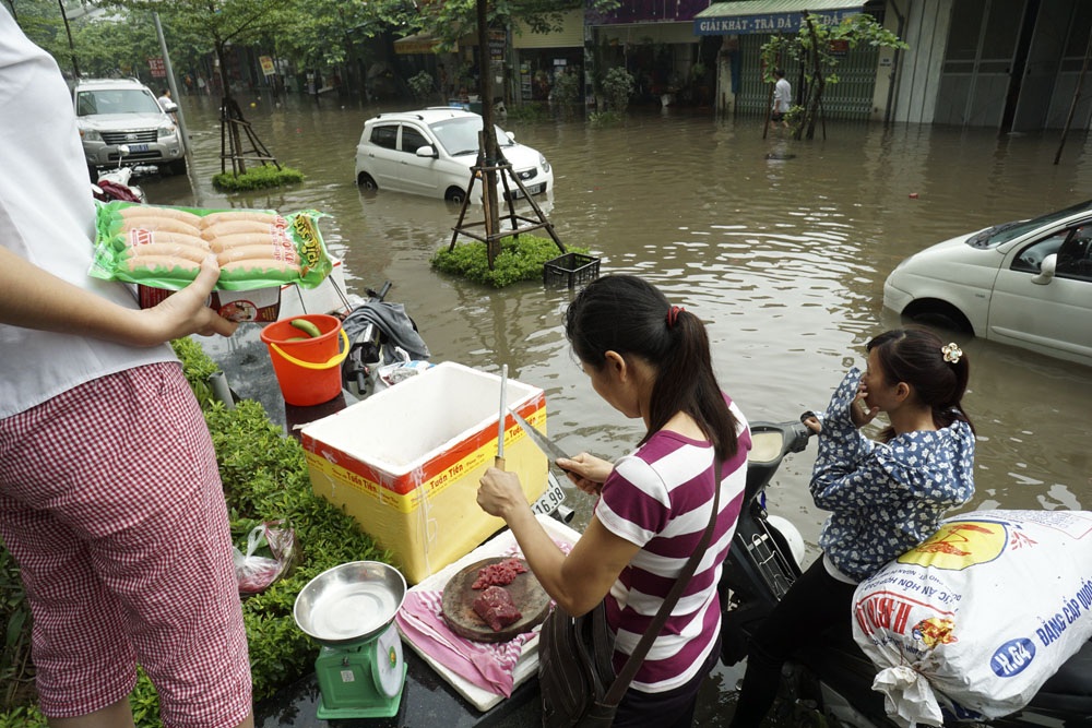 Khu Văn Phú - Hà Đông bị cô lập, người dân bàng hoàng với biển nước - 8 Dưới chân tòa chung cư Victoria Văn Phú, những người bán rau thịt lưu động kéo đến bày bán ngay bên lề đường phục vụ người dân trong cảnh đi lại khó khăn.