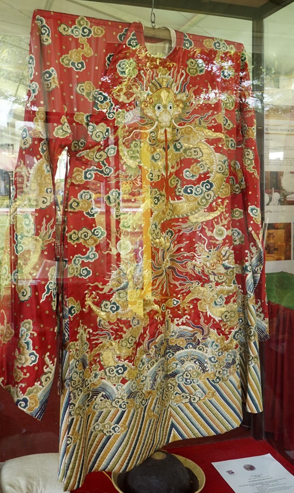 
Áo mãng bào Hoàng tử được nghệ nhân Vũ Văn Giỏi (Thường Tín, Hà Nội) cùng 7 cộng sự lành nghề thực hiện trong gần một năm, mục đích nhằm phục dựng trang phục cung đình. Chất liệu gồm lụa tơ tằm chập 8 sợi, chỉ tơ tằm se hai chiều nhuộm thảo mộc màu ngũ sắc, kim tuyến vàng, kim xa khuy áo.
