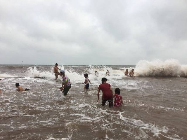 Tắm biển ngay trên bờ đê khi sóng lớn biến đường đi... thành bãi tắm - 4 Trẻ em nô đùa với sóng biển ngay trên đường