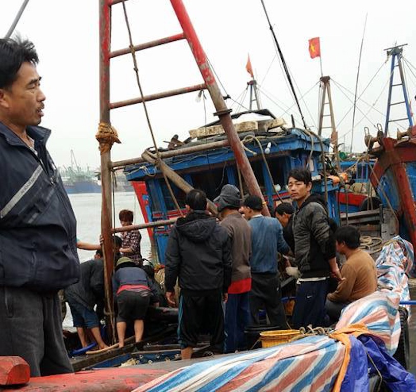 Các ngư dân cùng lực lượng chức năng trục vớt tàu cá chìm dưới biển đưa lên bờ.