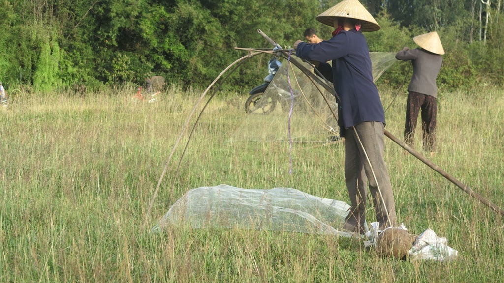 Người phụ nữ chuẩn bị lại chiếc vó, một dụng cụ đánh cá truyền thống trước giờ khai hội.
