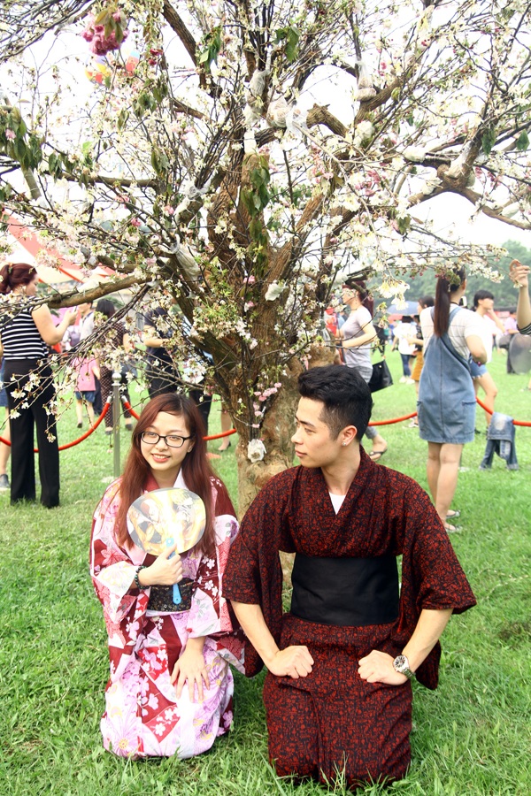 Một đôi bạn trẻ chụp ảnh lãng mạn dưới gốc hoa anh đào