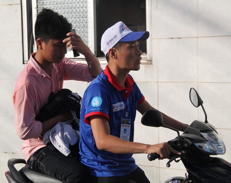 
Một thí sinh đến chậm vì quên giấy báo dự thi được các tình nguyện viên chở đến điểm thi tại Đại học Quy Nhơn. (Ảnh: Doãn Công)
