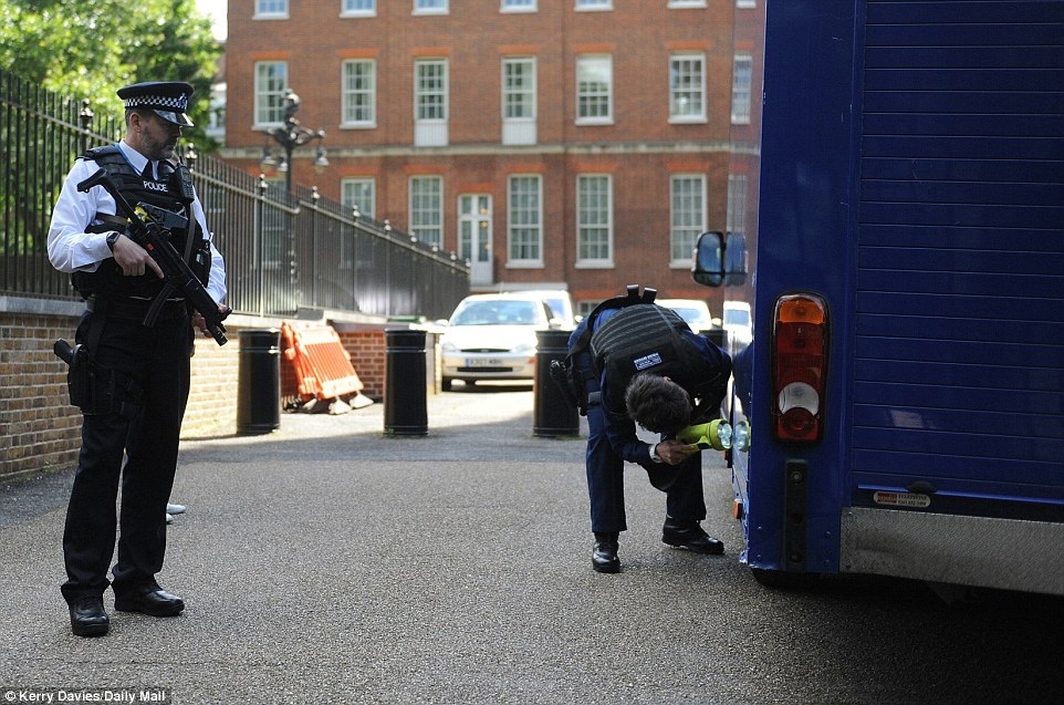 Một cảnh sát soi đèn pin kiểm tra xe tải bên ngoài dinh thủ tướng trong khi các cảnh sát khác luôn trong trạng thái canh chừng cẩn mật đội ngũ vận chuyển đồ (Ảnh: Dailymail)