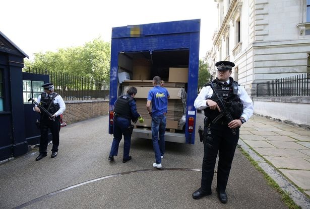 Trong khi công tác đóng gói đang được tiến hành bên trong căn nhà, ở bên ngoài, các cảnh sát vẫn không rời chiếc xe tải nửa bước (Ảnh: PA)