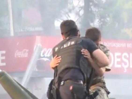 Sau đó viên cảnh sát giang tay ôm người lính để bảo vệ anh này (Ảnh chụp từ clip)