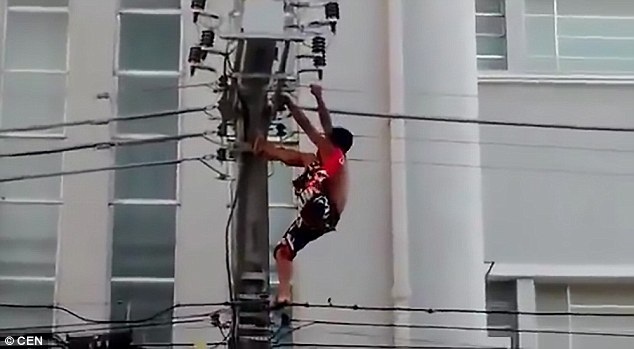 Brazil: Bị giật chết khi trèo lên cột điện nghe Tổng thống phát biểu - 1 Người đàn ông cố tình tìm cách leo lên cột điện cao thế bất chấp lời khuyên từ đám đông bên dưới (Ảnh: CEN)