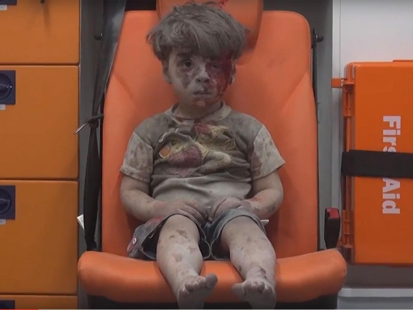 Nhói lòng hình ảnh cậu bé bị thương sau cuộc không kích ở Syria - 1 Omran Daqneesh ngồi thất thần trên xe cứu thương sau khi được giải cứu khỏi một ngôi nhà bị sập do không kích ở Syria. (Ảnh: Independent)