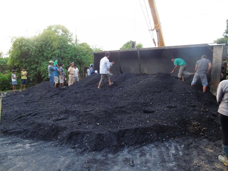 Người dân phụ giúp tài xế xe tải xúc than ra khỏi thùng xe