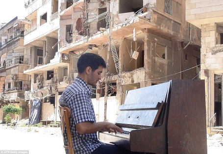 Điều kỳ diệu từ cây đàn dương cầm đặt trên hè phố - 2 Ayham al-Ahmed, một người Palestine sống trong trại tị nạn Yarmuk ở thành phố Damascus, Syria, đang chơi dương cầm đặt trên một con phố có những tòa nhà bị đổ sập.