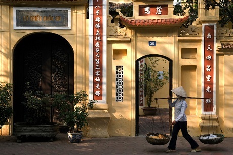 Một người phụ nữ gồng gánh đi ngang qua chùa Lý Quốc Sư, Hà Nội.