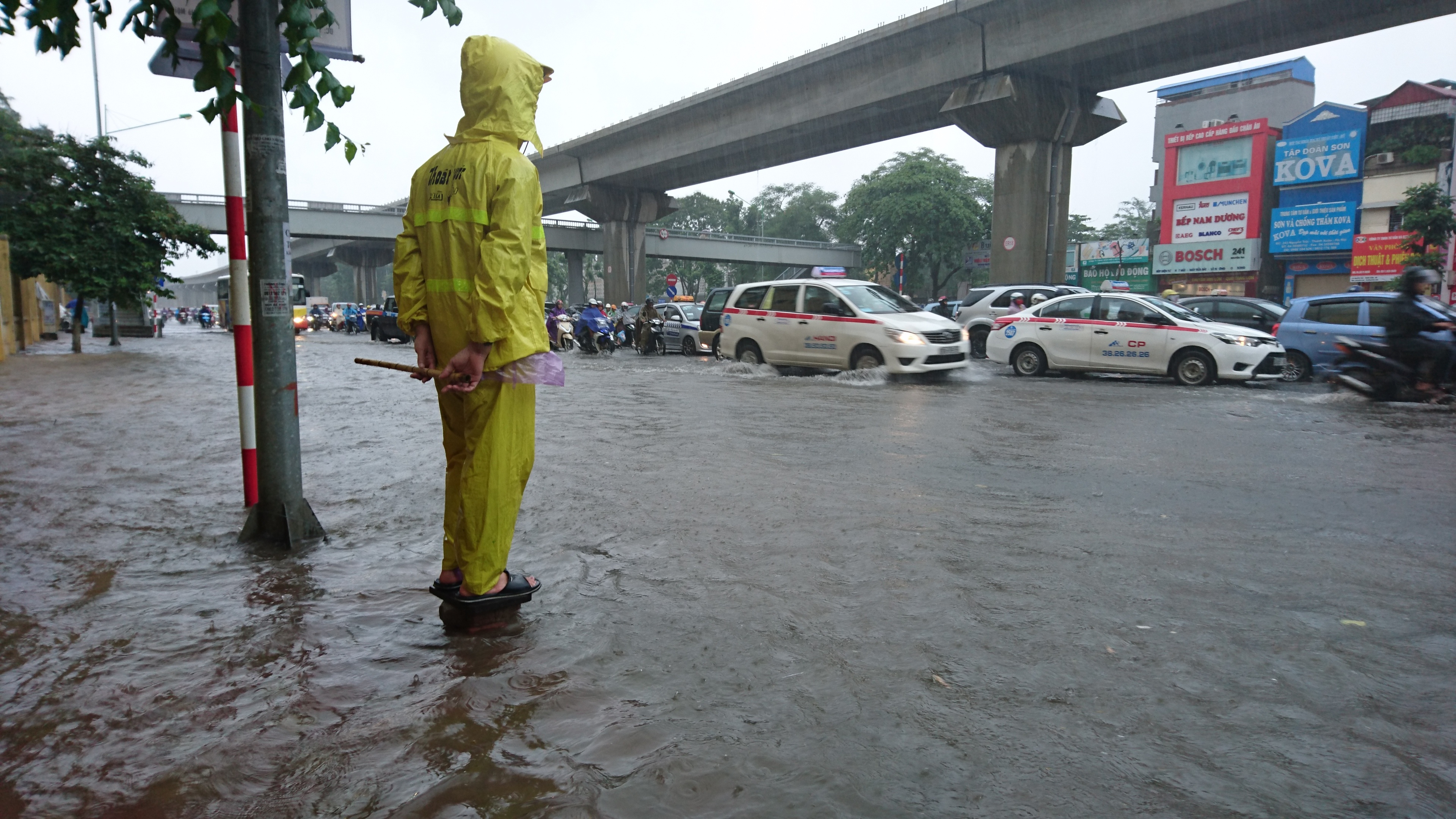 
Công nhân thoát nước đứng cảnh báo điểm ngập sâu cho người tham gia giao thông.
