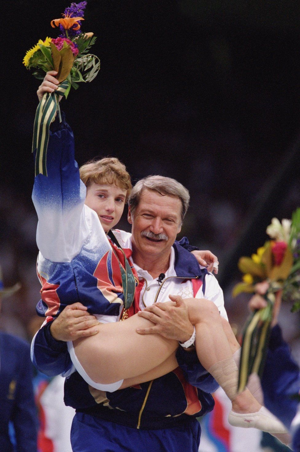 Những bức ảnh “đắt” nhất trong lịch sử các kỳ Olympic - 6 VĐV thể dục dụng cụ, Kerri Strug đã dính chấn thương sau bài thi ở Olympic 1996. HLV đã bế cô trên tay sau khi giành Huy chương vàng. Người hâm mộ có thể cảm nhận được niềm hạnh phúc trên gương mặt của hai người
