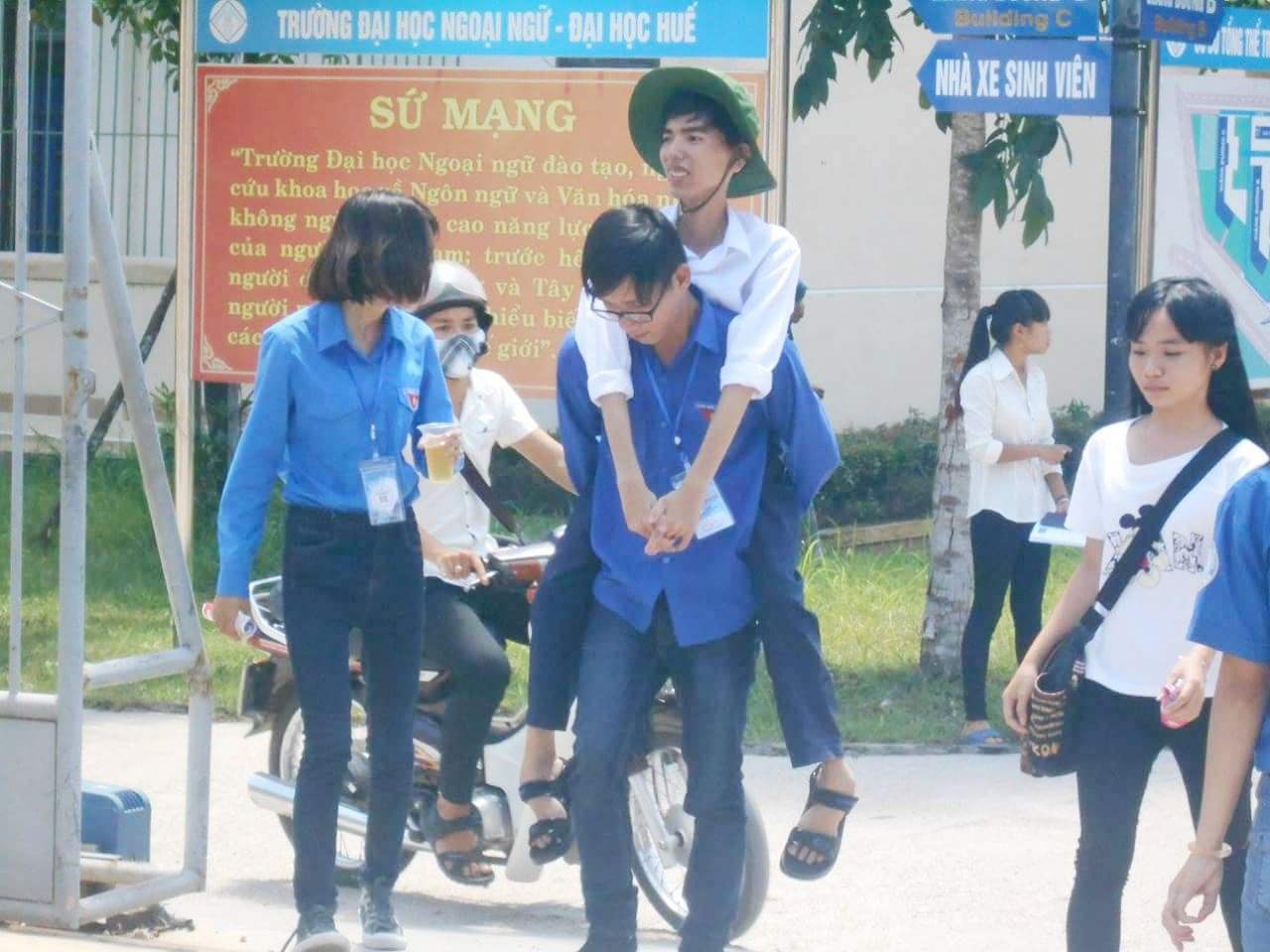 Thí sinh teo chân được cõng vào phòng thi mỗi ngày - 1 Các tình nguyện viên đang đón bạn Cường từ cổng hội đồng thi
