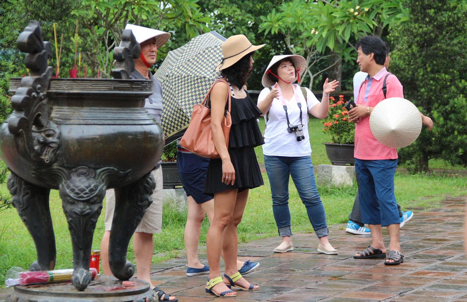 Người phụ nữ Hàn Quốc (áo trắng) vừa nói vừa chỉ tay về chính điện của chùa với các vị khách trong đoàn