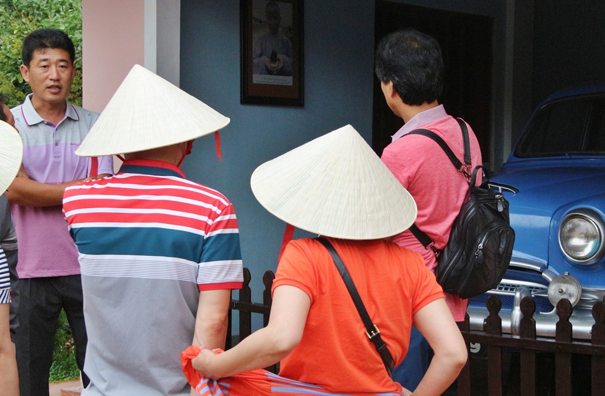 Một người Hàn Quốc (áo xám xanh, khoanh tay ở bìa trái ảnh) tự làm HDV trong đoàn của mình trước khu trưng bày của chùa Thiên Mụ