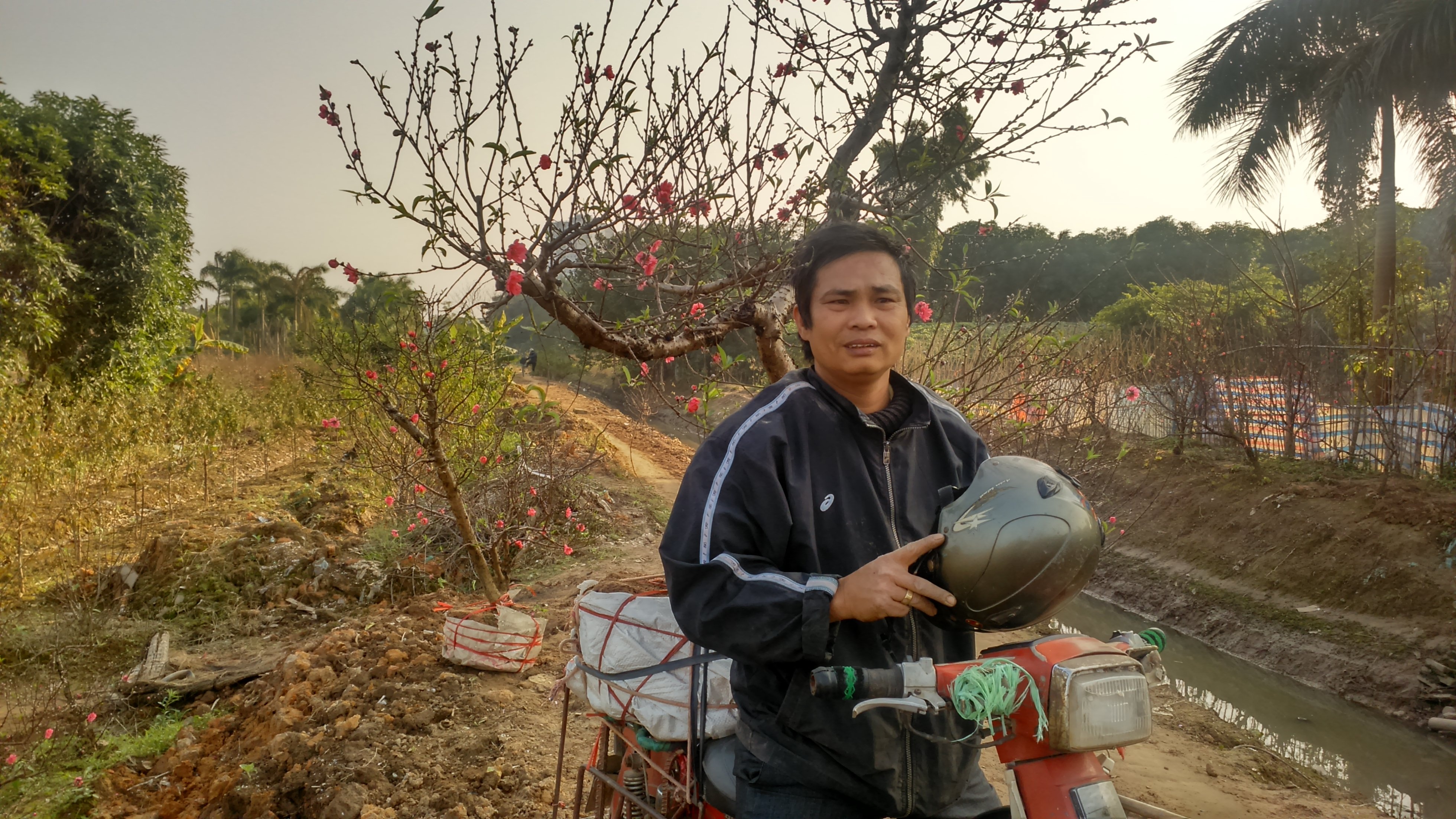 Bác xe ôm chuẩn bị cho chuyến hành trình 30km của mình. Mỗi ngày, hơn 10 lượt chở đào, dù mệt nhưng kiếm được tiền nên ông rất vui