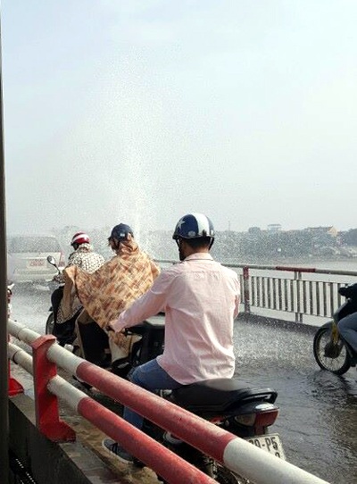 Nước phun xối xả trên cầu Chương Dương, người qua cầu mặc áo mưa giữa trời nắng - 2 Mặc áo mưa qua cầu dù trời không mưa.