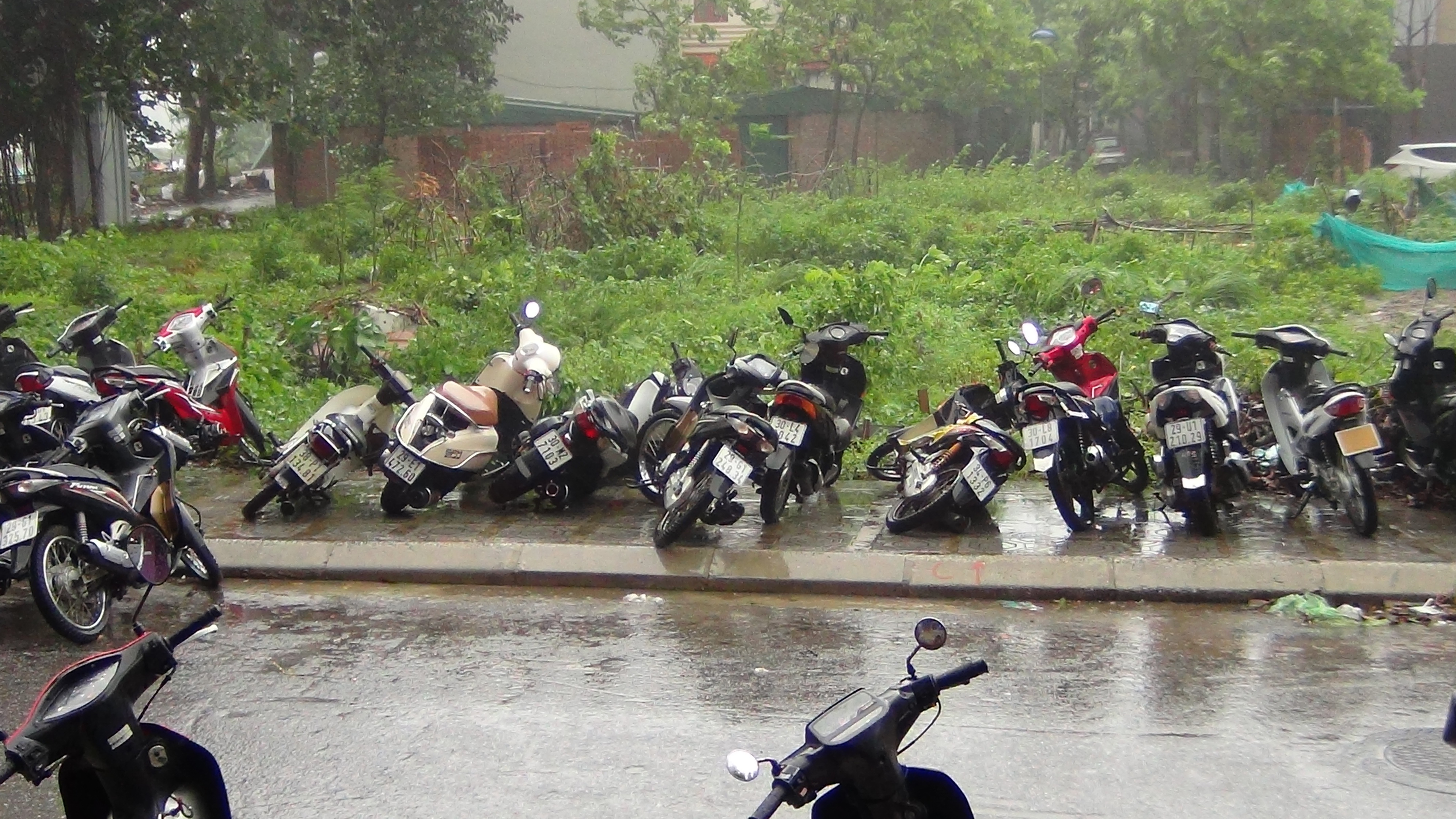 Gió thổi đổ hàng loạt xe máy dưới chân tòa nhà cao tầng