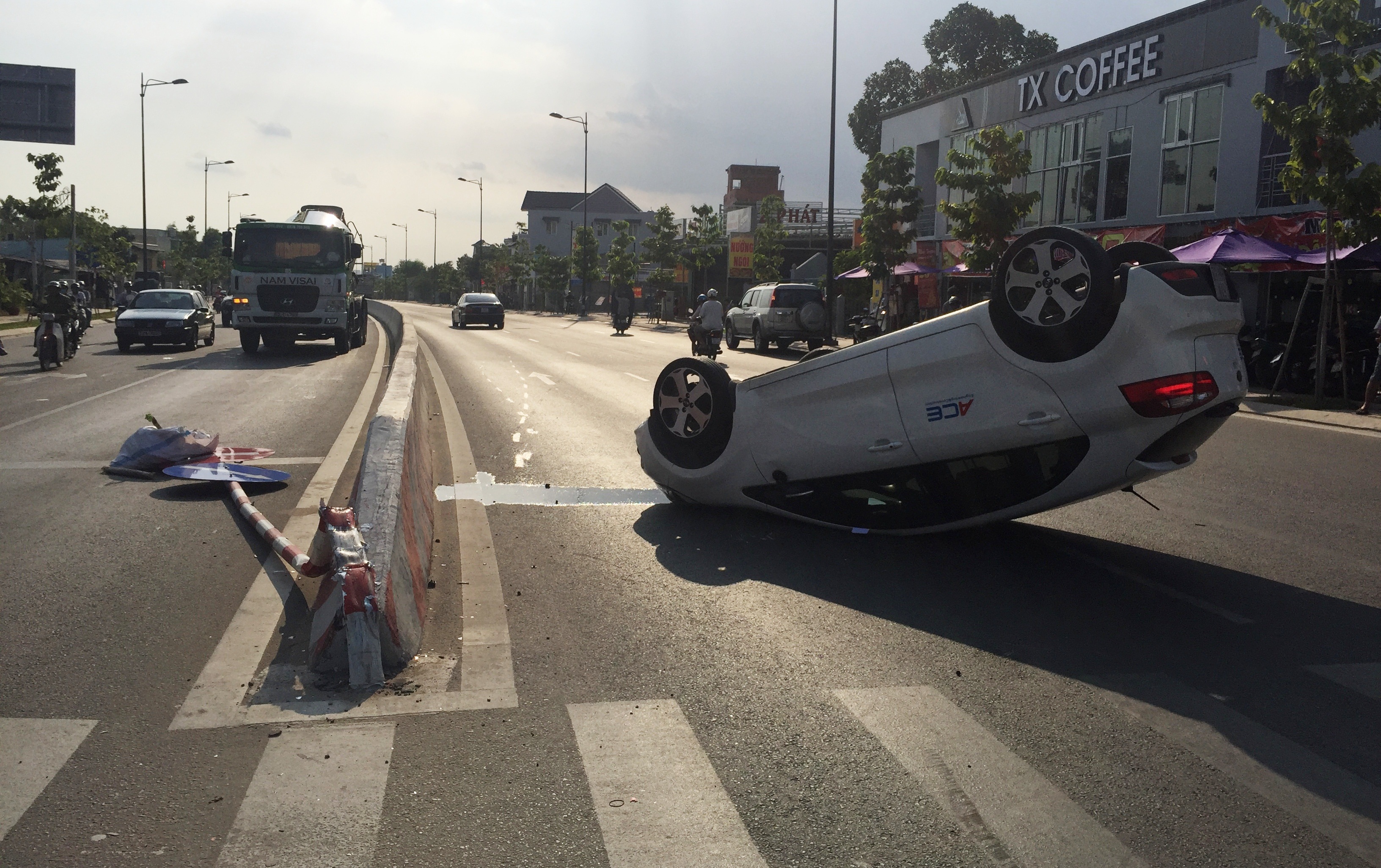 Chiếc du lịch 4 chỗ bất ngờ lao vào dải phân cách, tông gãy biển báo giao thông rồi lật ngữa giữa đường Phạm Văn Đồng.