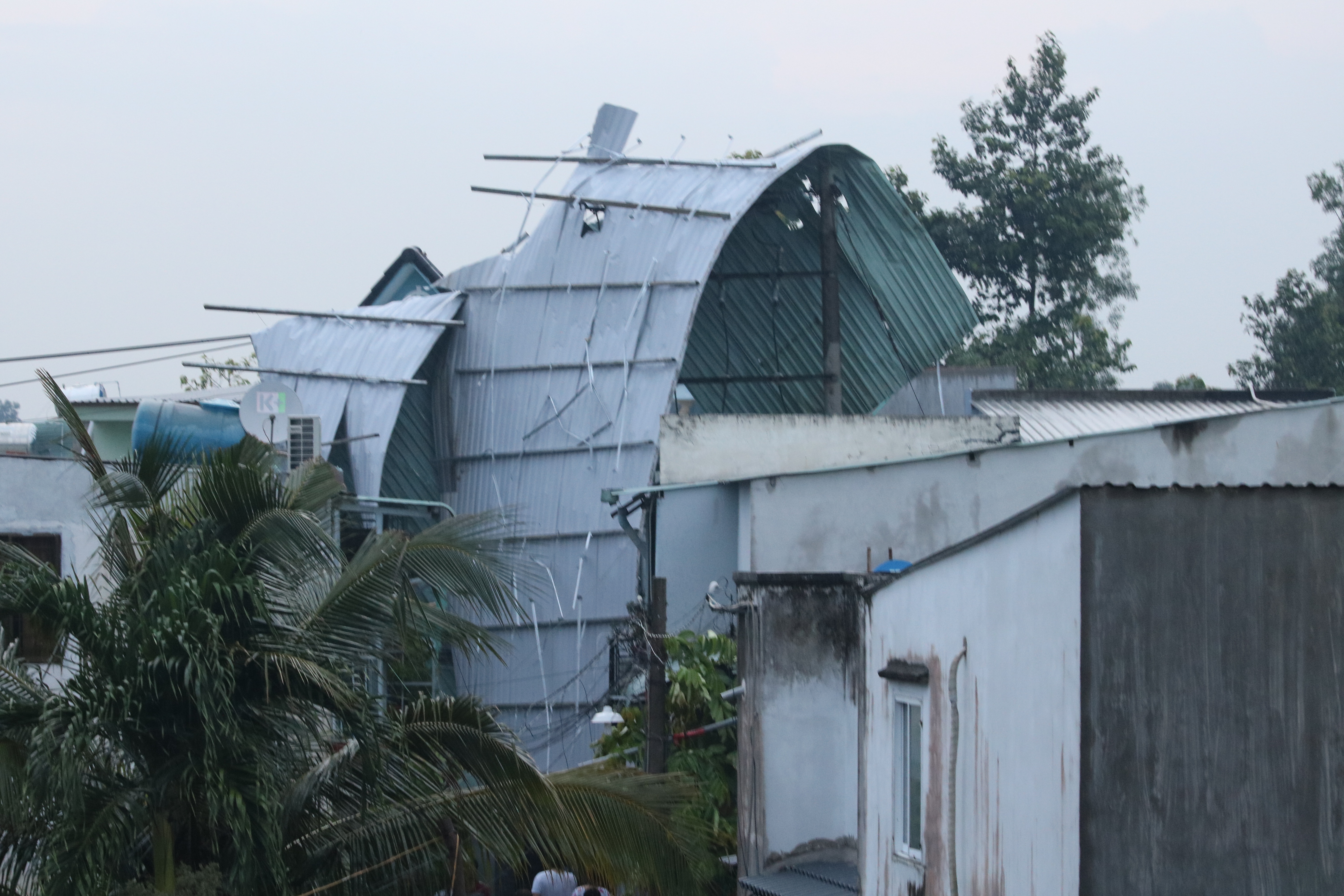 Mái tôn có diện tích khủng khiếp bị cuốn bay hàng trăm mét vắt ngang trụ điện trên đường số 17 phường Long Thạnh Mỹ.