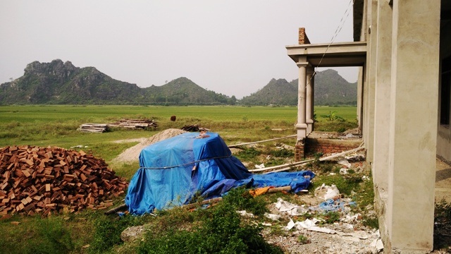 Trường xây nhiều năm chưa xong, ban giám hiệu phải làm việc trong... chợ - 2 Vật liệu xây dựng vương vãi khắp nơi, cỏ dại mọc um tùm quanh công trình hàng tỷ đồng