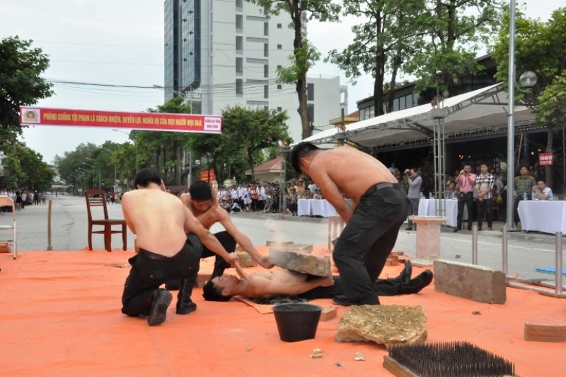 Cảnh sát đặc nhiệm nằm trên bàn chông, công phá đá - 2 Một chiến sĩ Cảnh sát đặc nhiệm nằm trên các mảnh thủy tinh, để một hòn đá to trên bụng cho đồng đội công phá.