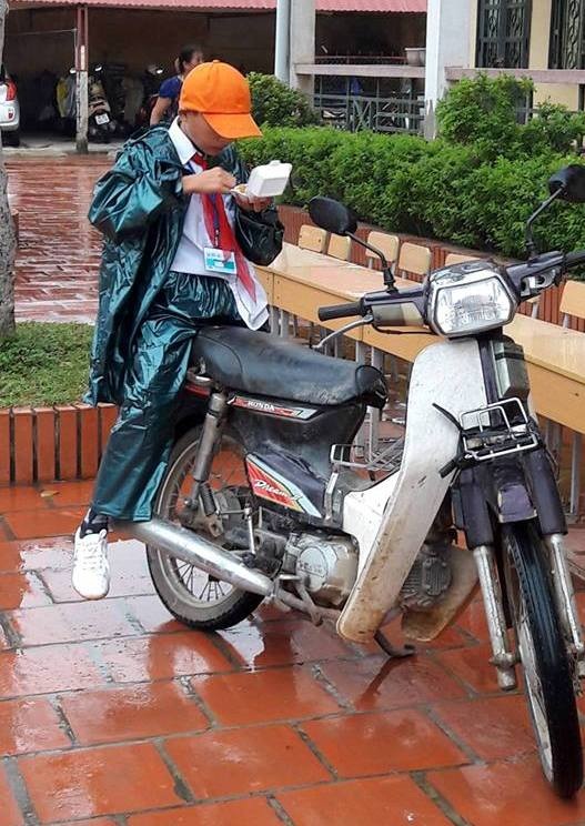 Phụ huynh đội mưa đưa con đi khai giảng - 1 Một cậu học sinh tranh thủ ăn bữa sáng trong lúc đến trường