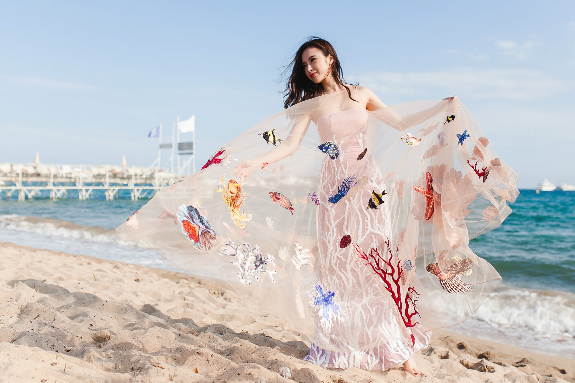 Trang phục của Angela Phương Trinh tại Cannes được khen ngợi - 2 Trang phục được thiết kế từ chất liệu vải organza, saphia và lưới. Các họa tiết sinh vật biển được in hoàn toàn trên chất liệu vải saphia, đính vào trang phục cùng pha lê và kim sa.