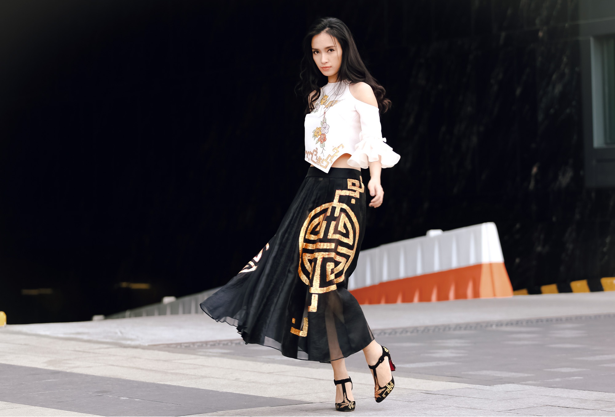 Ái Phương thướt tha với chiếc váy đen bồng bềnh trong gió, thân áo được tách rời theo kiểu áo yếm cách điệu.