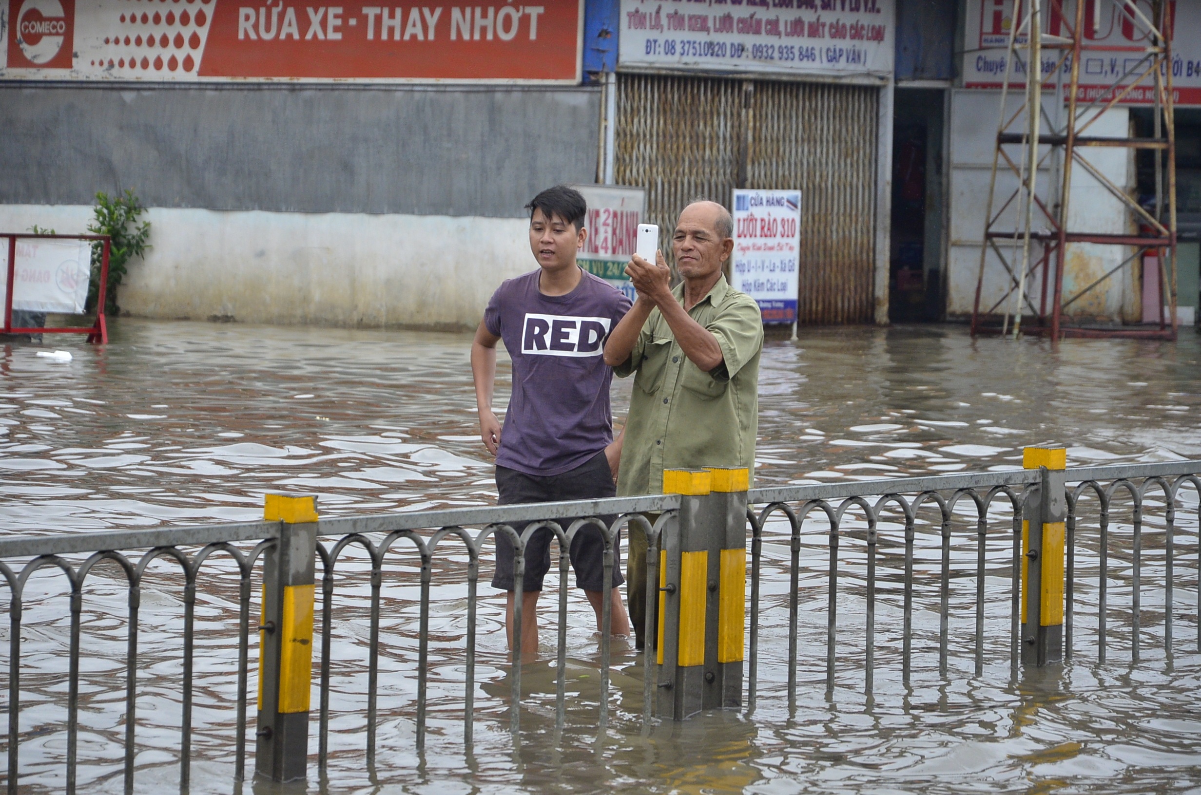 Một người dân đứng chụp hình giữa đường ngập