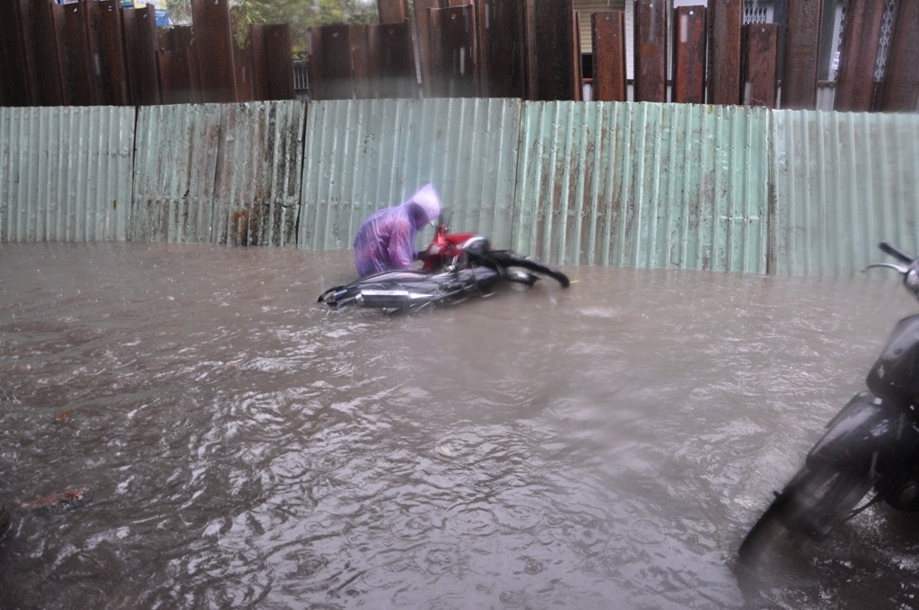 Một người điều khiển xe máy bị té ngã trong biển nước