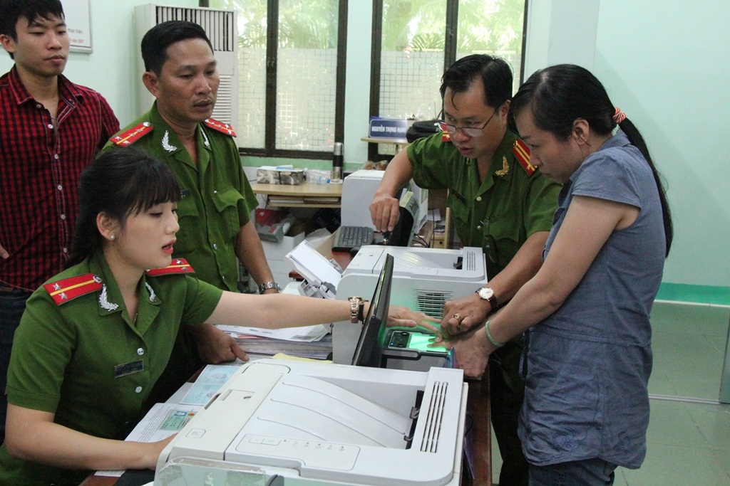 
Cán bộ Đội chứng minh nhân dân hướng dẫn người dân lấy dấu vân tay bằng máy.
