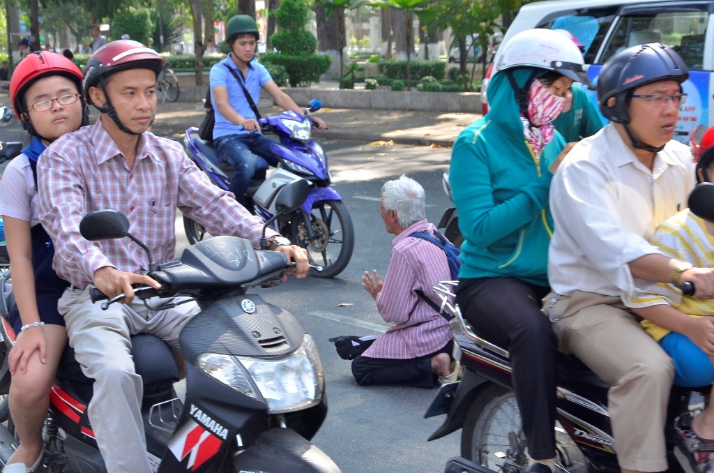 Ông này thậm chí qùy giữa dòng phương tiện qua lại đông đúc để xin tiền