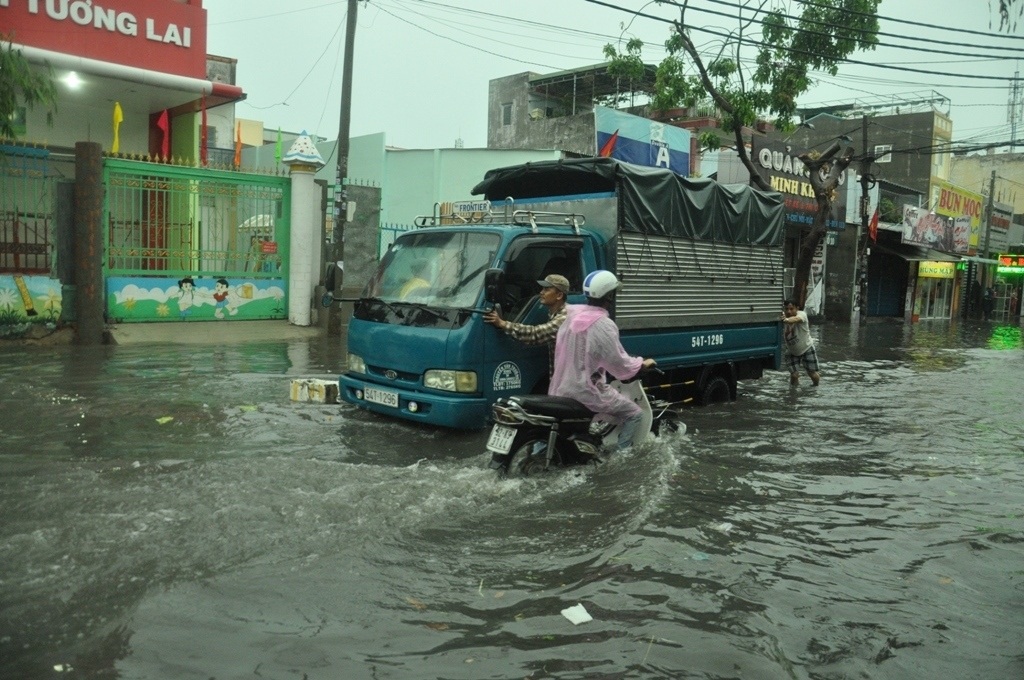 Lái và phụ xe hợp sức đẩy chiếc xe tải chết máy qua vùng ngập