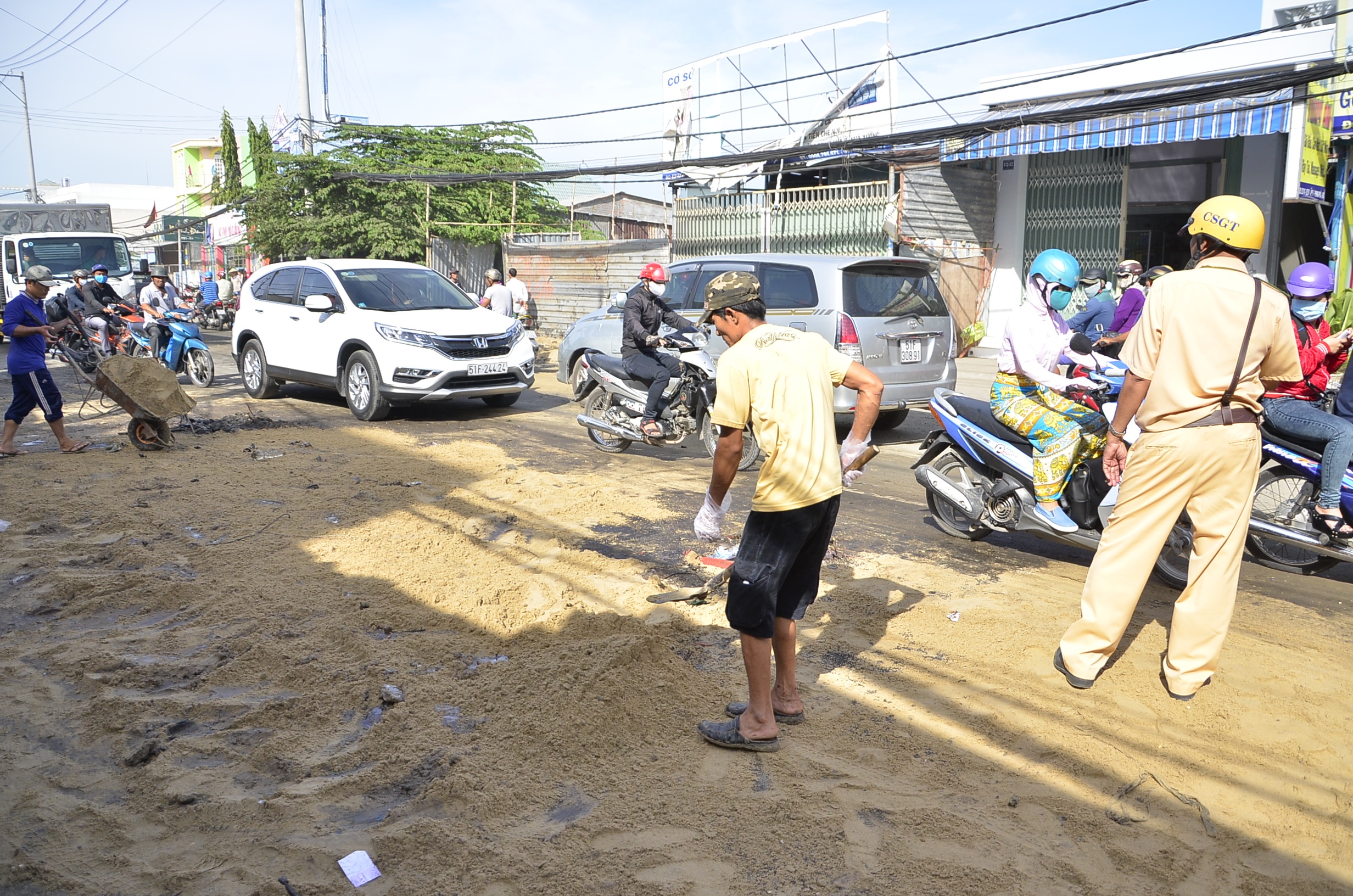 
Người dân phủ cát lên dầu và bùn để đảm bảo an toàn giao thông.
