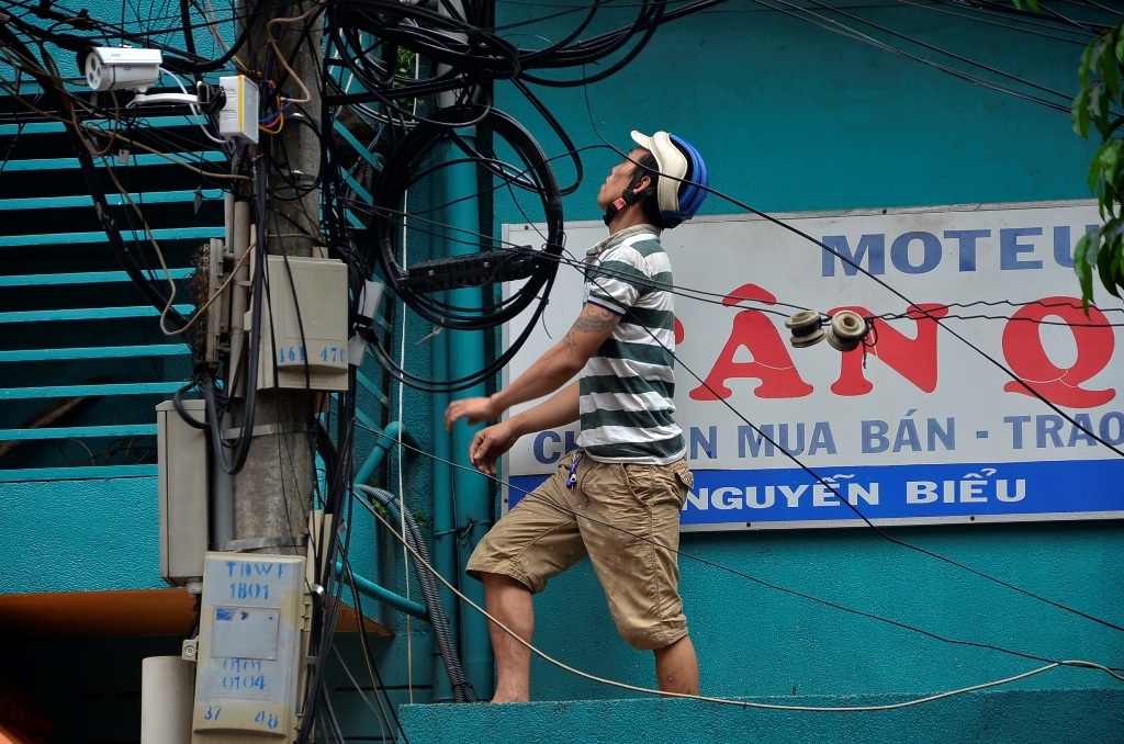 
Một thanh niên trèo lên ban công sát trụ điện để nhặt tiền.
